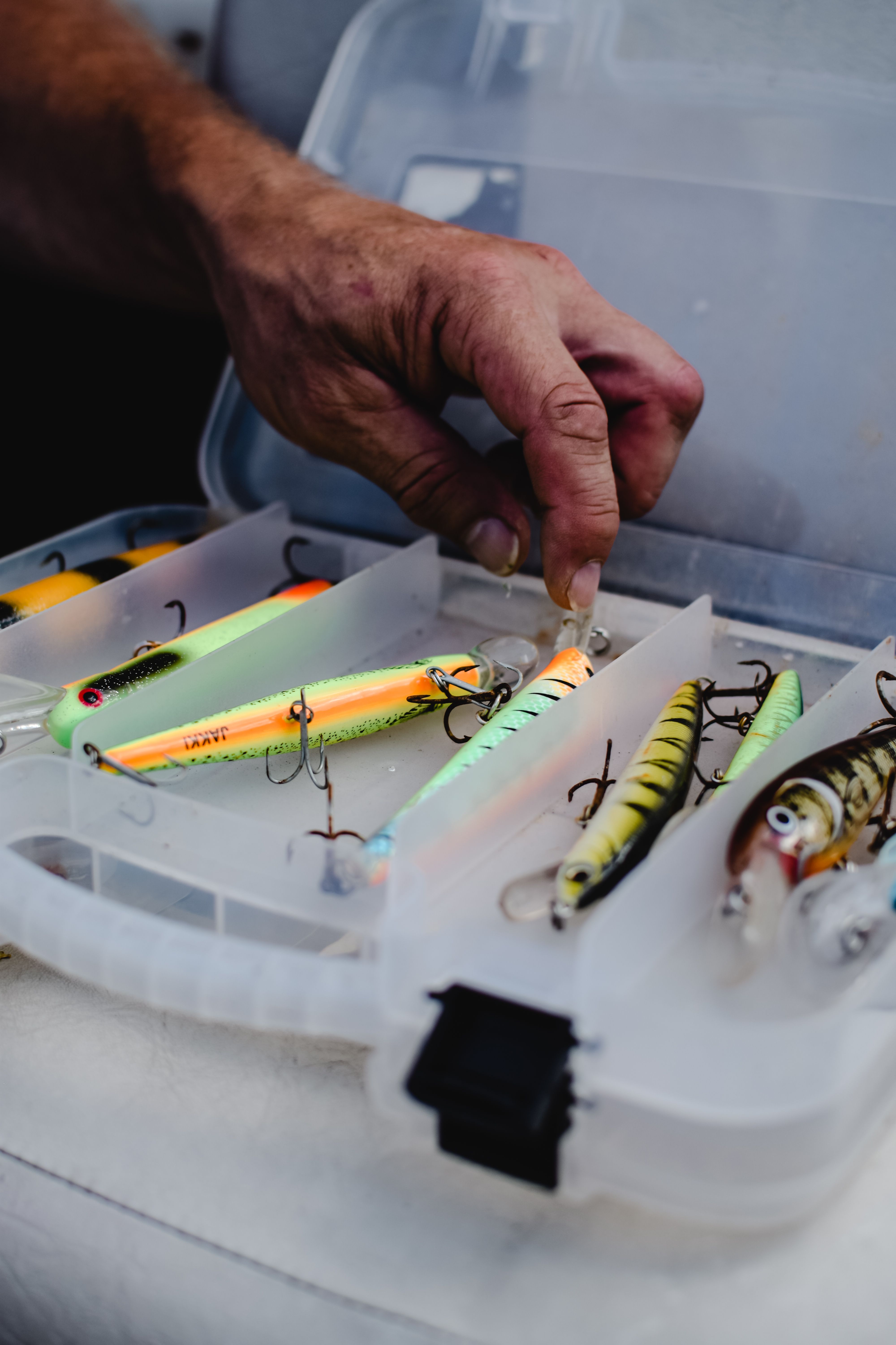 Angler selecting colorful fishing lures from a tackle box
